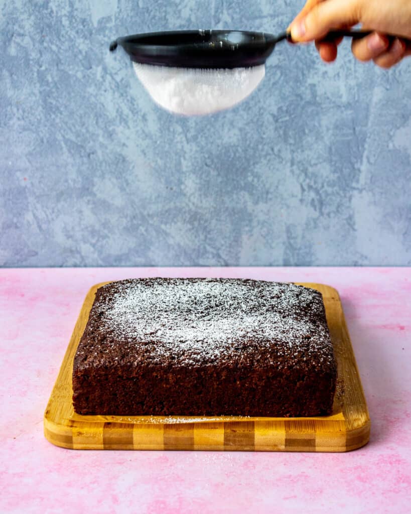 dusting confectioners sugar on top of cake