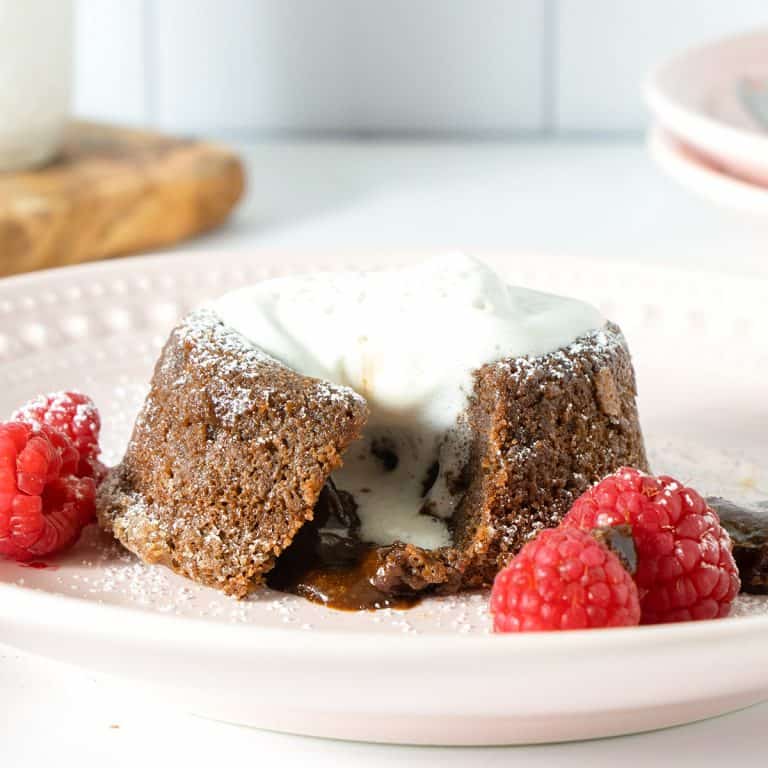 Gluten-Free Chocolate Lava Cake on a pink plate with raspberries and whipped cream