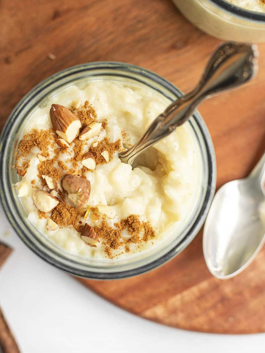 oat milk rice pudding in a small glass jar with a spoon