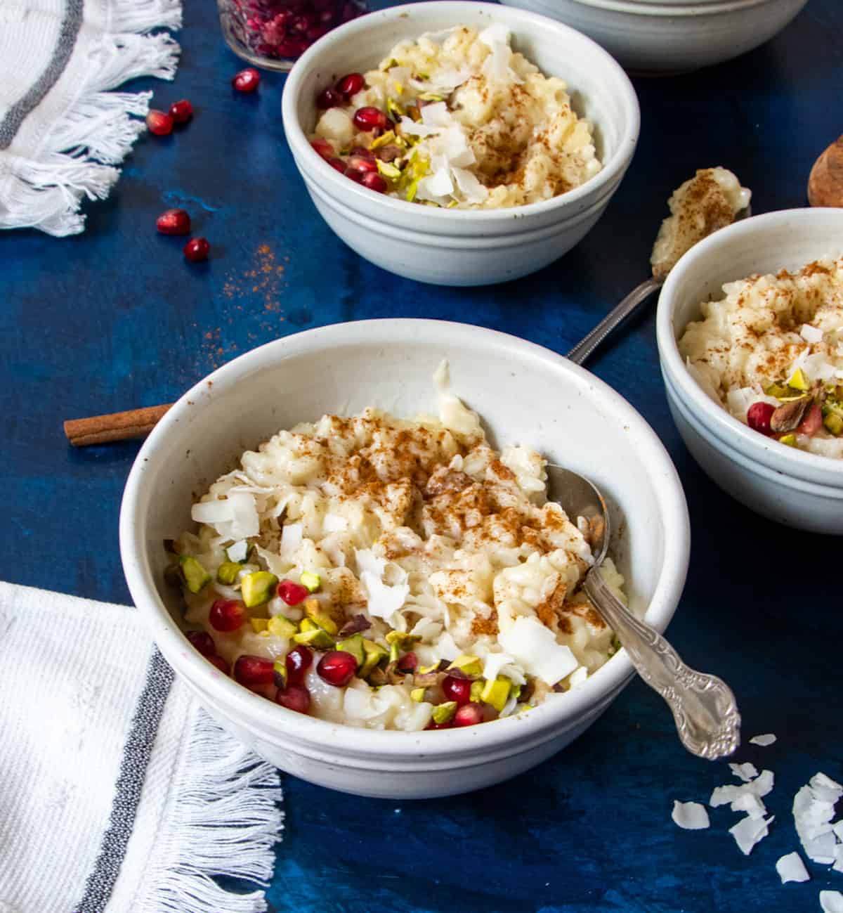 oat milk rice pudding in three bowls with a towel