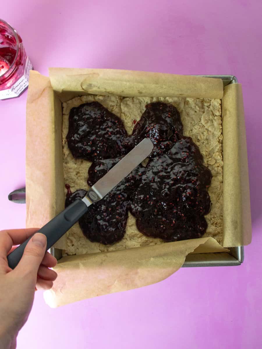 spread raspberry jam onto gluten free raspberry bar crust