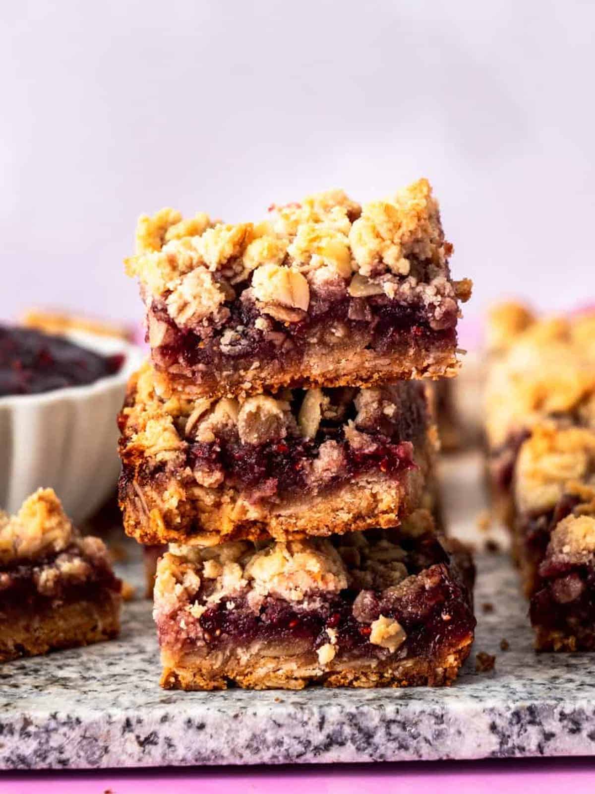 stacked gluten free raspberry bars on marble counter 