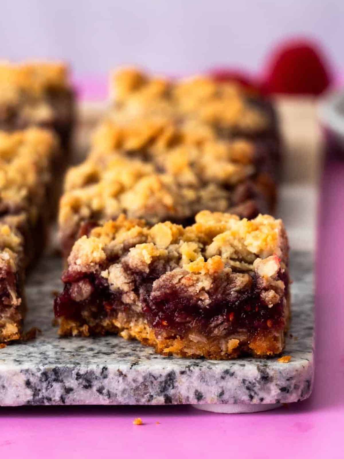 gluten free raspberry bar with bite taken out of it on marble surface