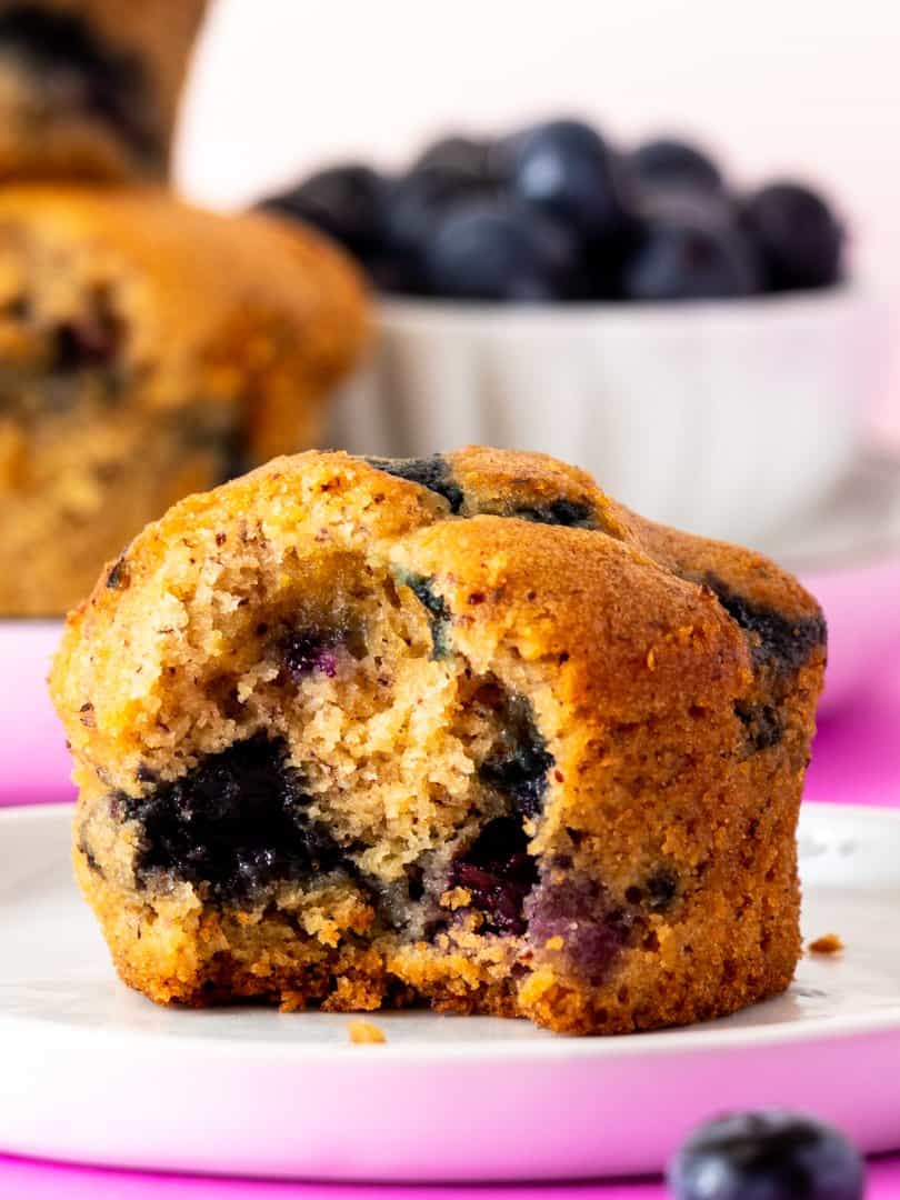 gluten free blueberry muffins with a bite taken on a white plate