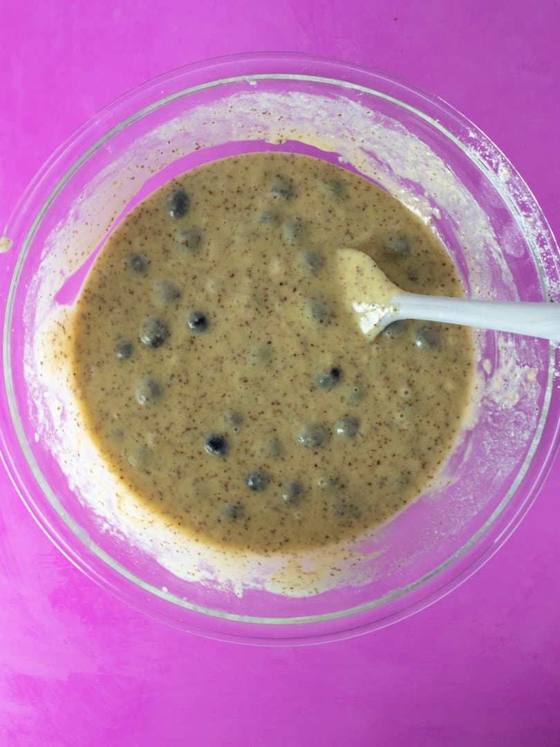 To Die For Blueberry Muffin batter in a glass bowl with a rubber spatula