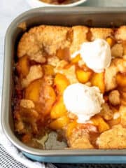 gluten free peach cobbler in a pan with scoop of ice cream