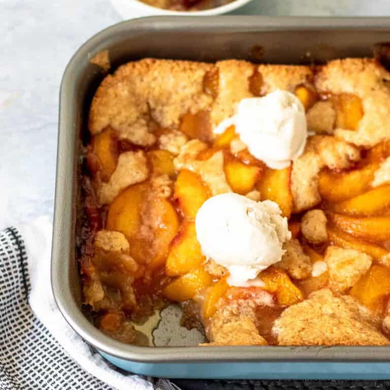 gluten free peach cobbler in a pan with scoop of ice cream