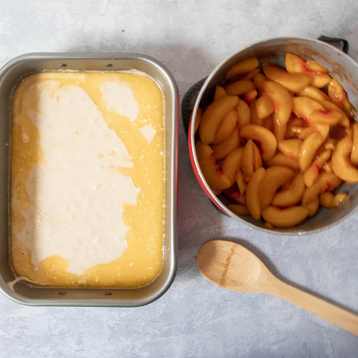 pan with butter and batter and peaches in a bowl