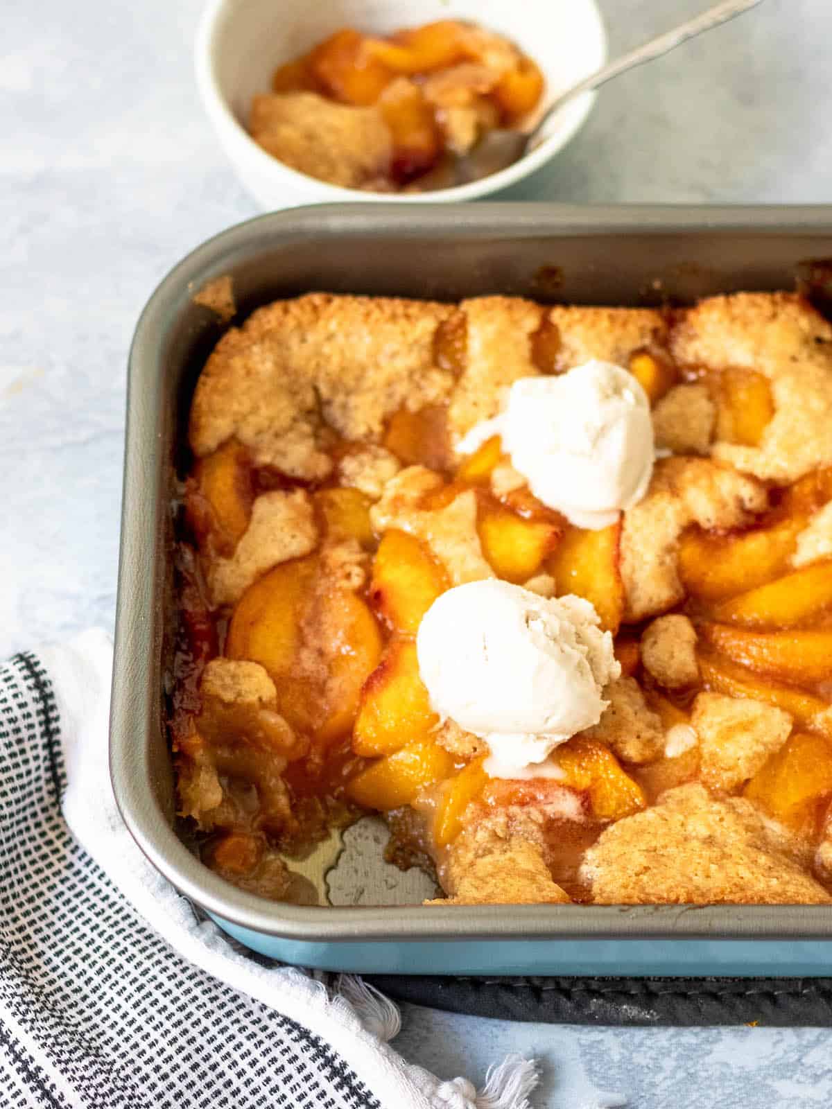 gluten free peach cobbler in pan with ice cream