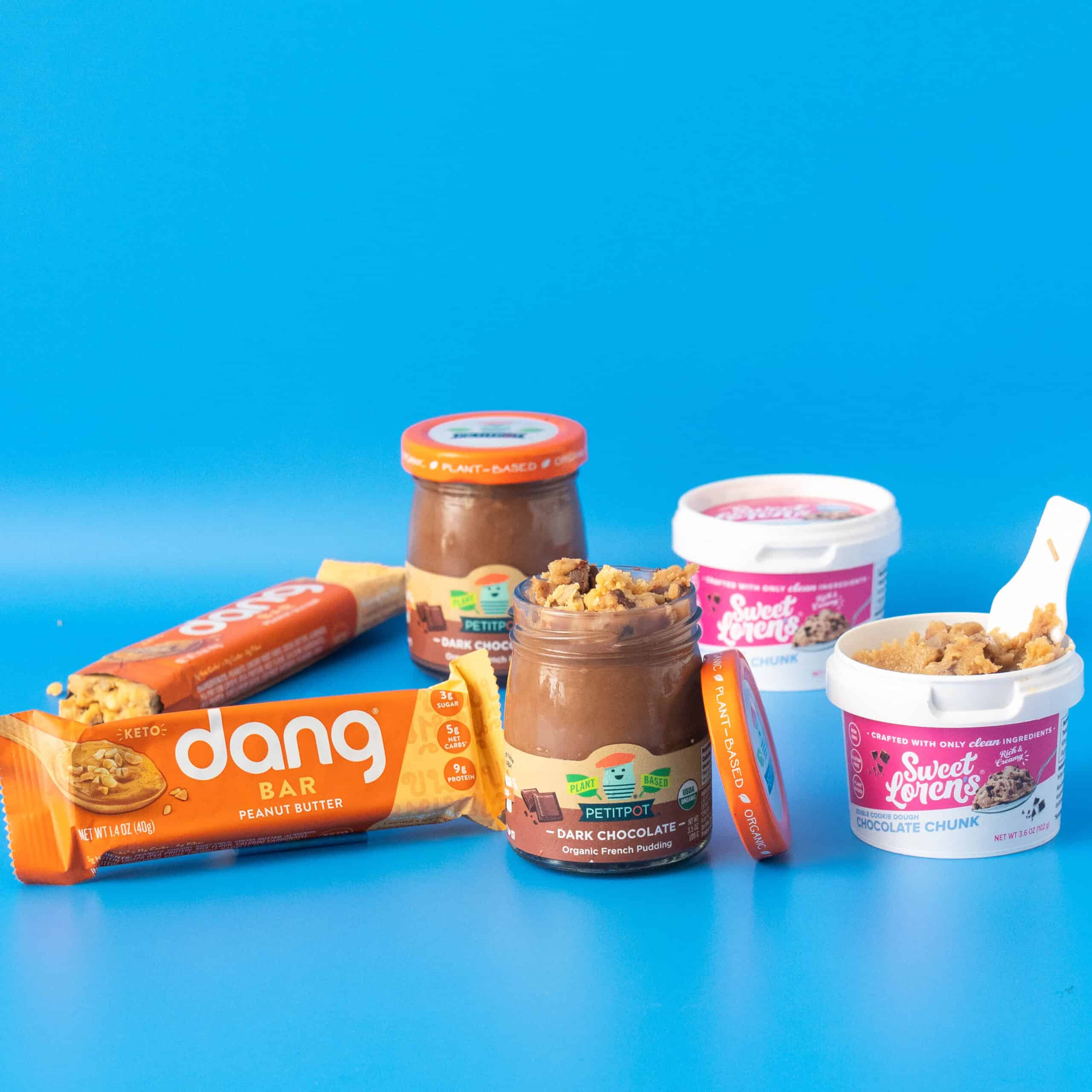 product image of petit pods chocolate pudding on a blue background. Sweet Loren's cookie dough and dang foods are also in the image.