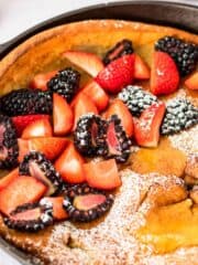 gluten free dutch baby in cast iron skillet with strawberries and blackberries