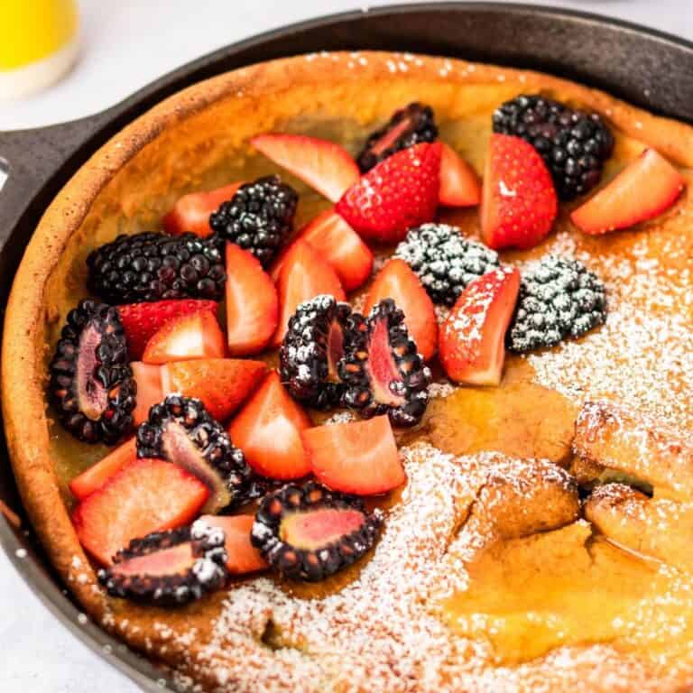 gluten free dutch baby in cast iron skillet with strawberries and blackberries