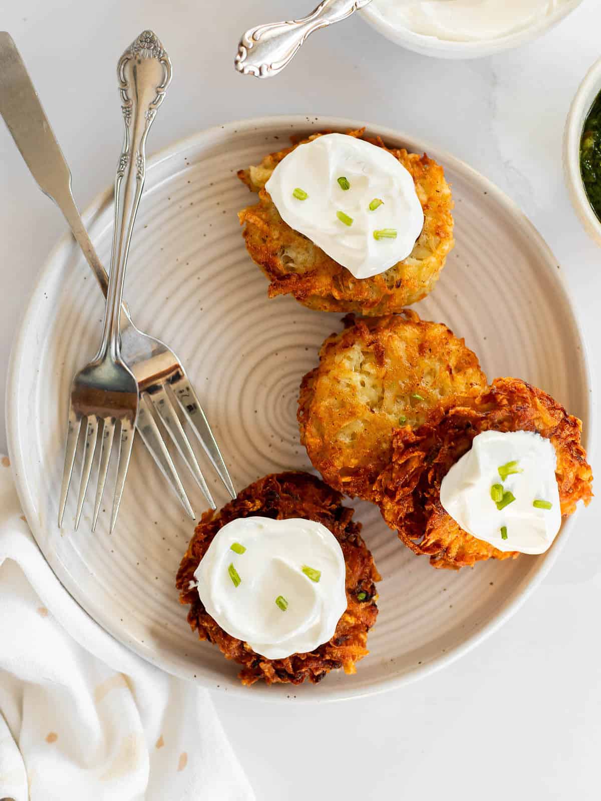 gluten free latkes on a plate with sour cream and chives