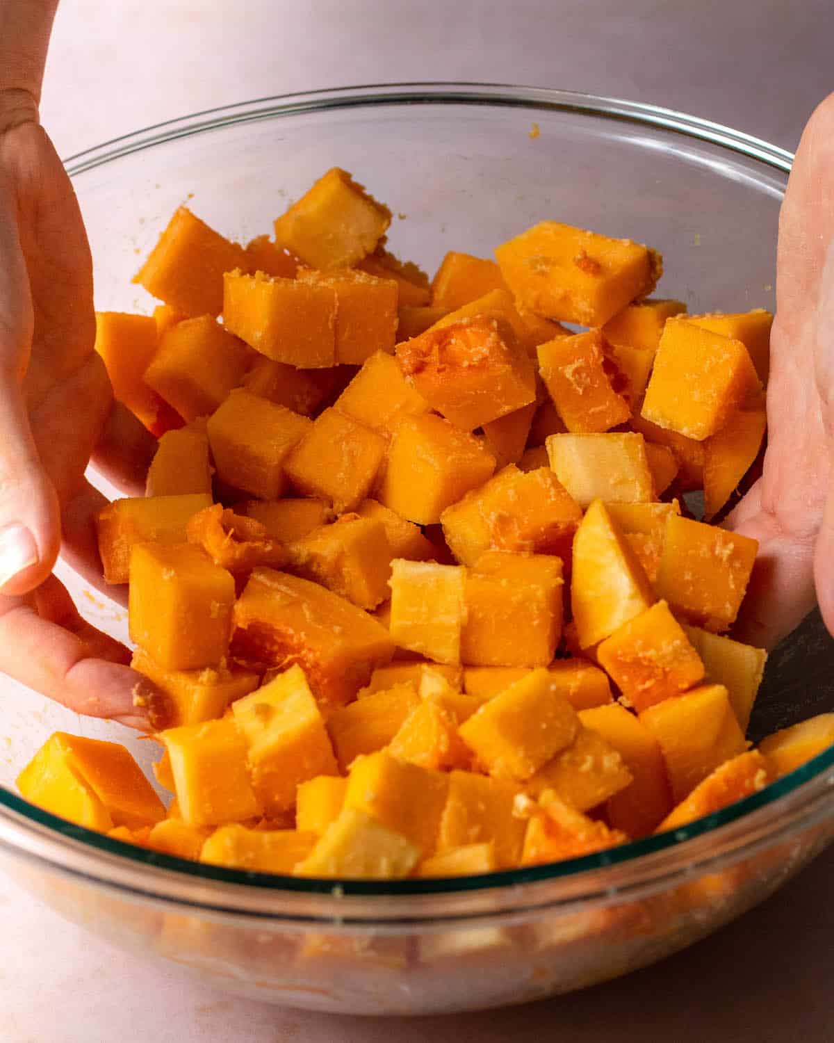 butternut squash cubes with miso in a bowl being mixed by hand
