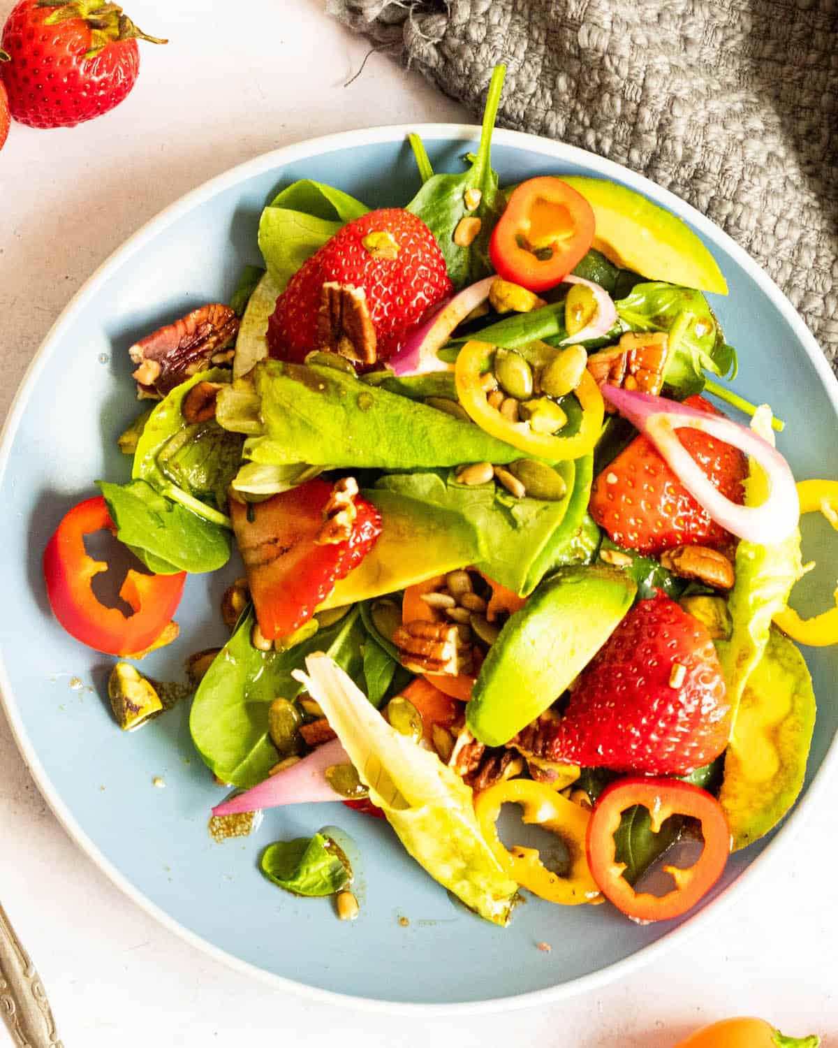 strawberry spinach salad on a medium blue plate