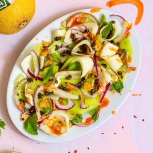 Summer Fennel Salad with Melon on a white dish with hot sauce and pink background
