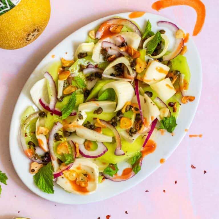 Summer Fennel Salad with Melon on a white dish with hot sauce and pink background
