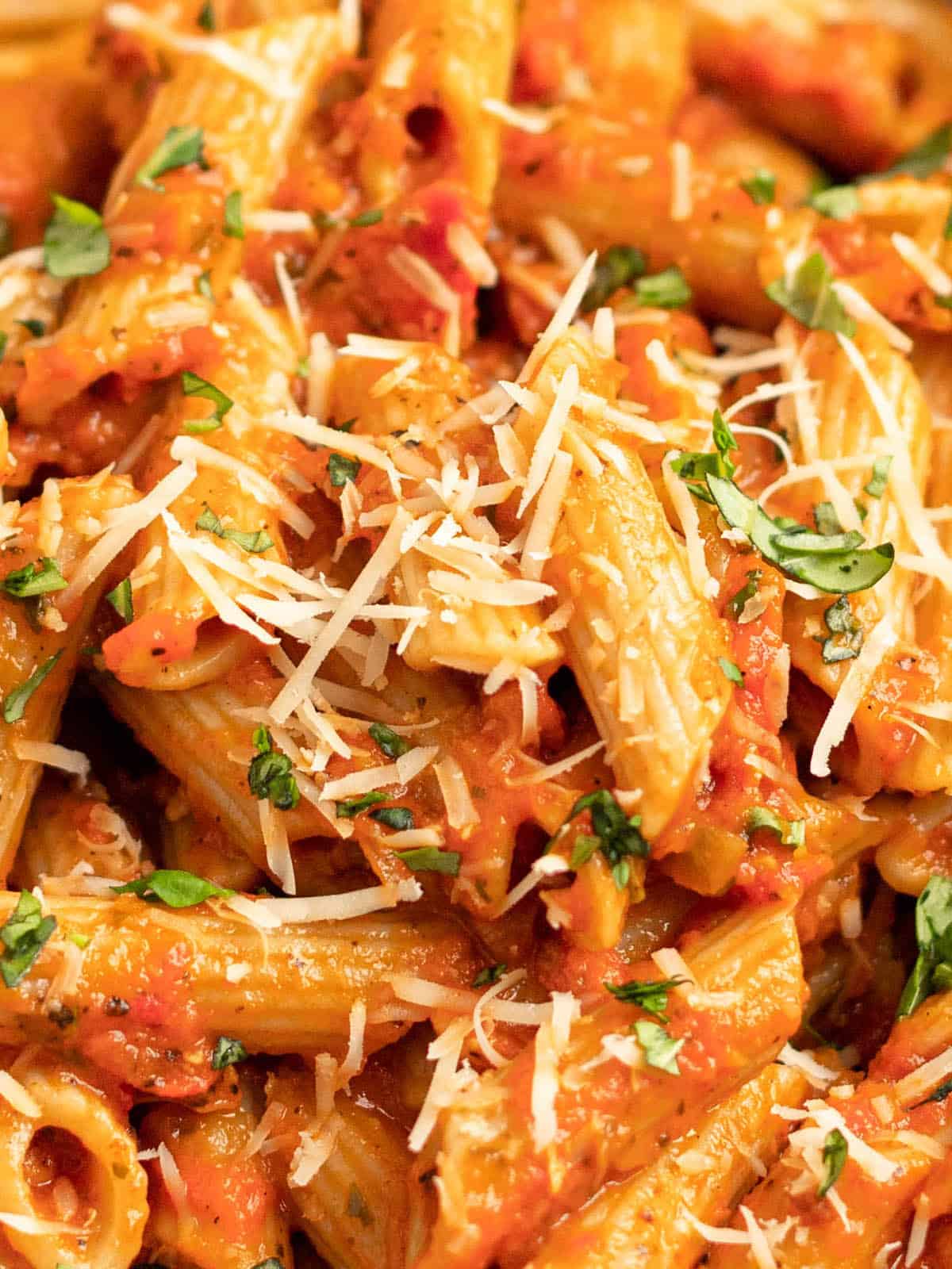 up close of pink sauce pasta with parmesan and basil