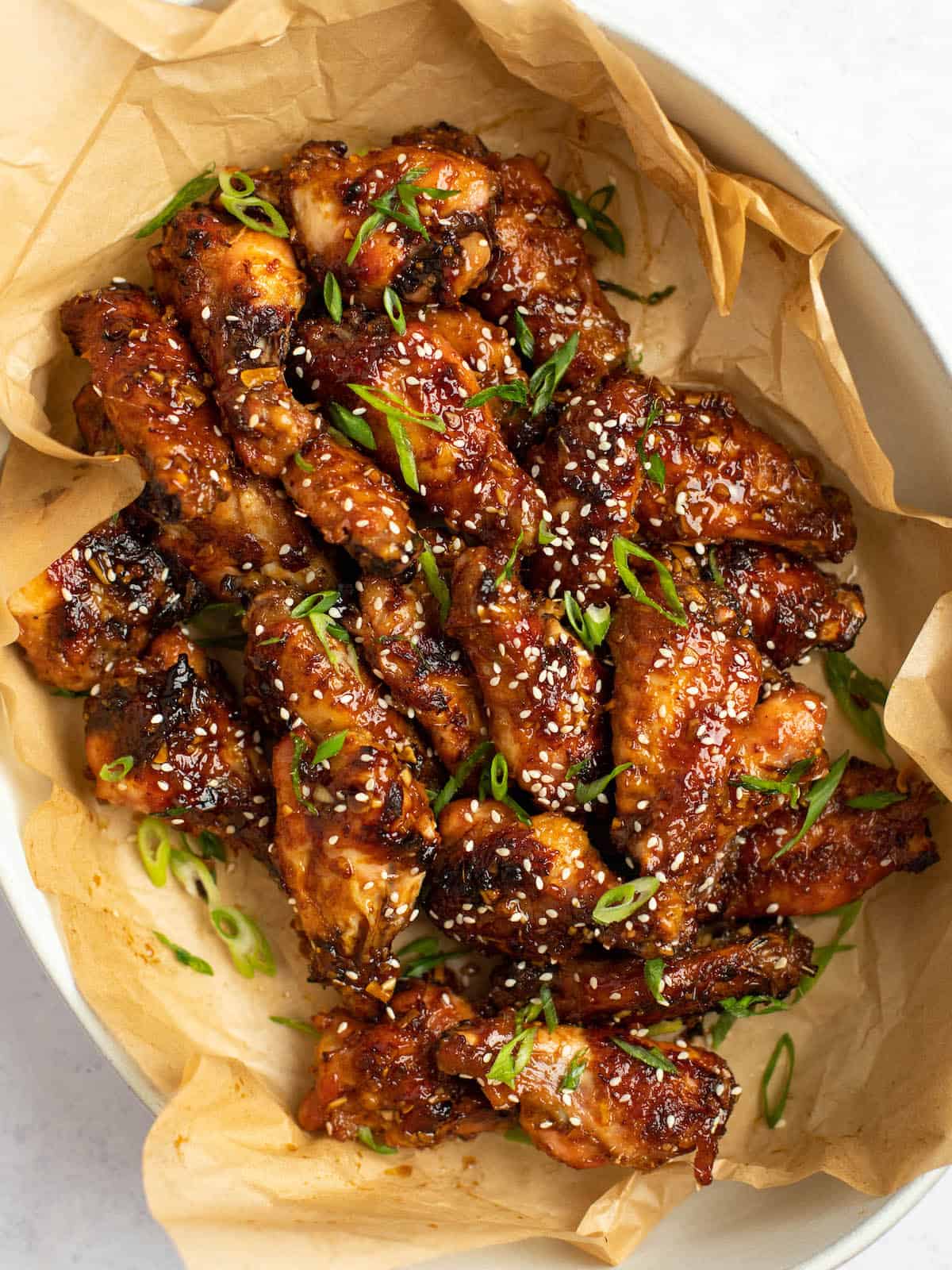 soy garlic chicken wings in a wide bowl with parchment paper