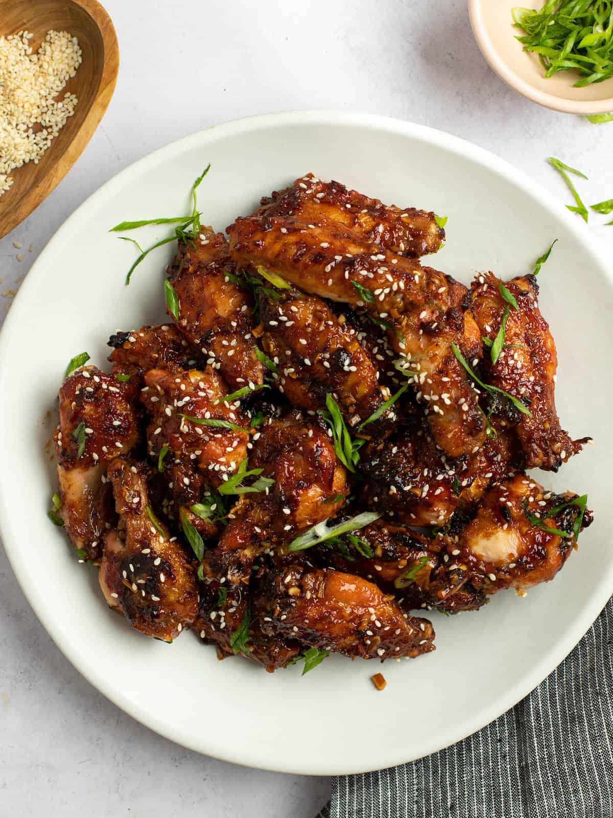 soy garlic chicken wings stacked on a white plate with a dish towel on the side