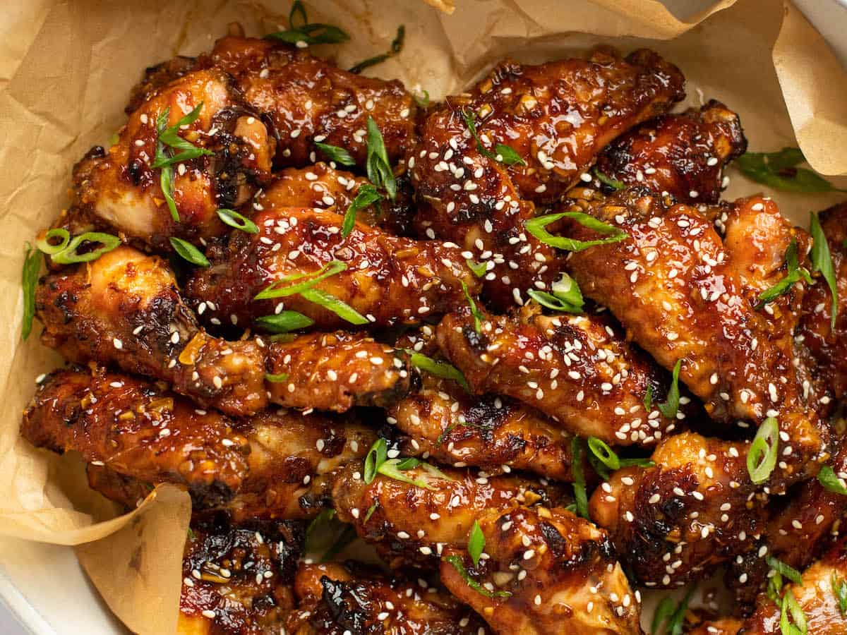 soy garlic chicken wings in a bowl with brown parchment paper and scallion garnish