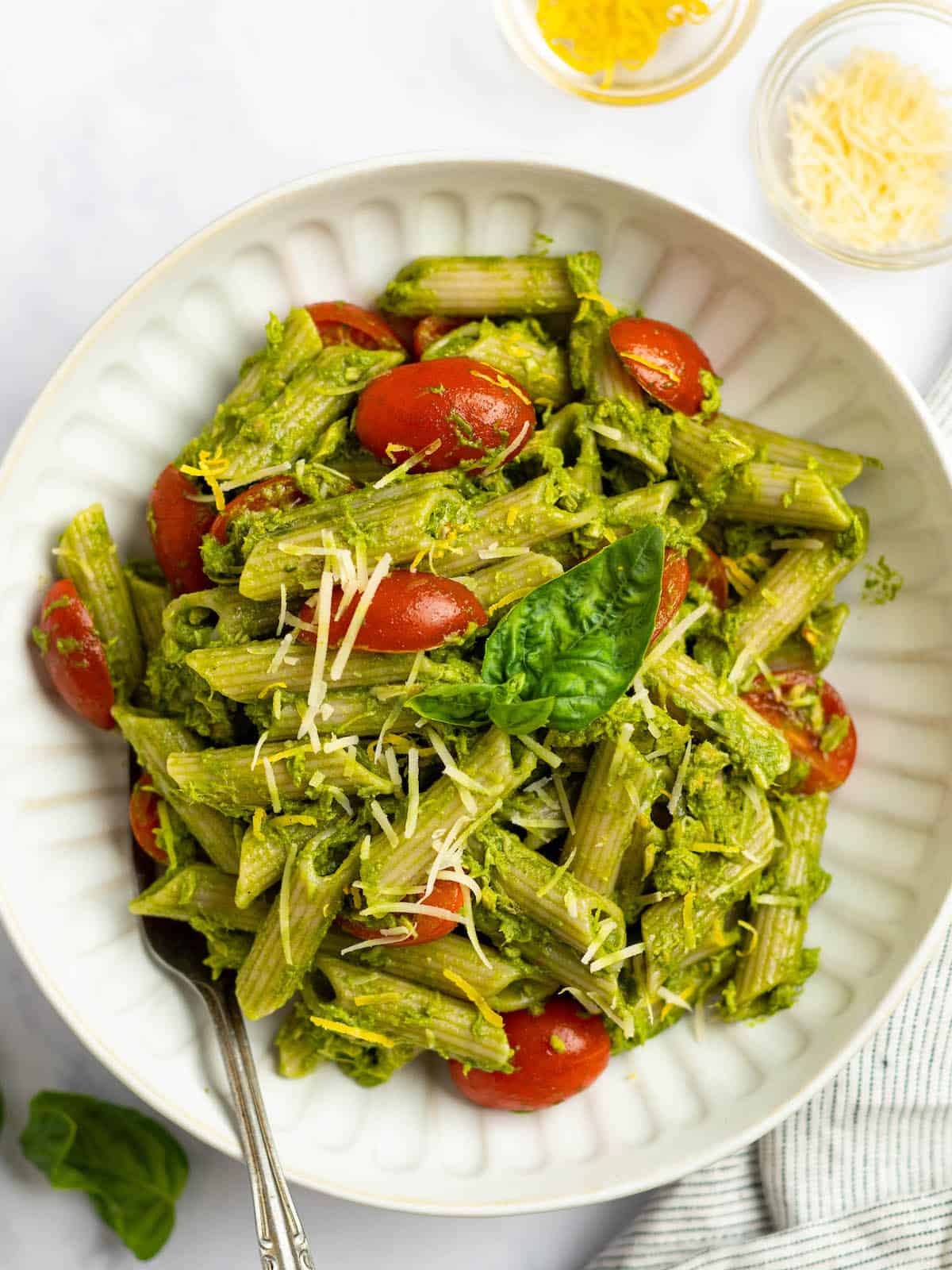 tuna pesto pasta with cherry tomatoes in a white bowl with parmesan 