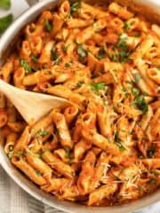 pink sauce pasta in skillet with a wooden spoon