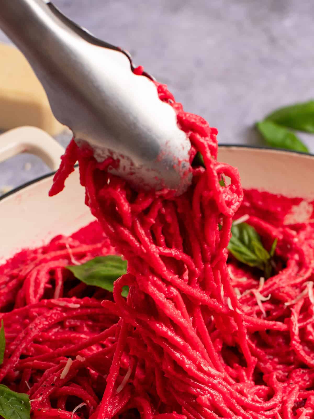 tongs twirling pasta that is pink like barbie