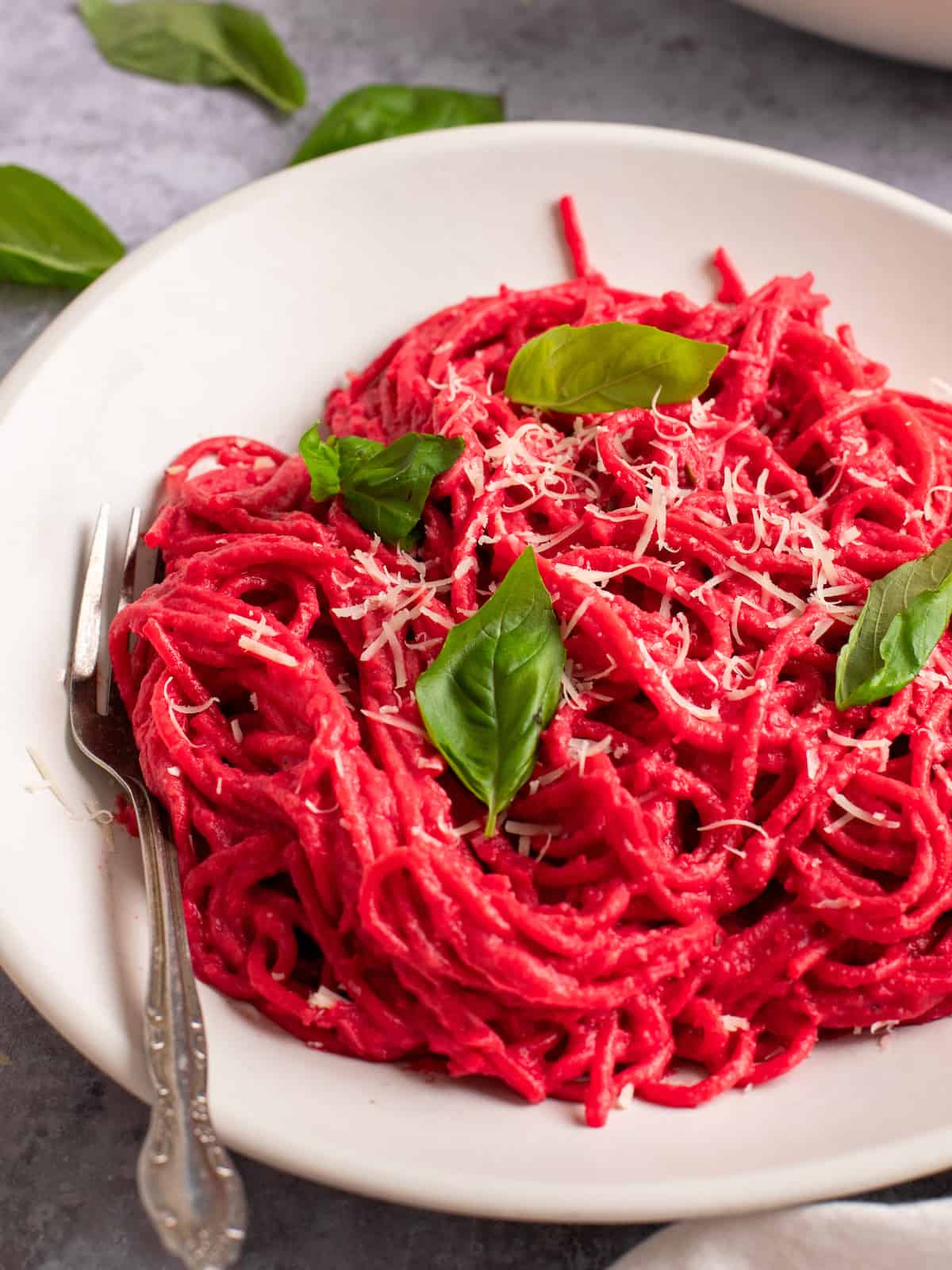 Pink barbie pasta made with beets on a white plate with a fork