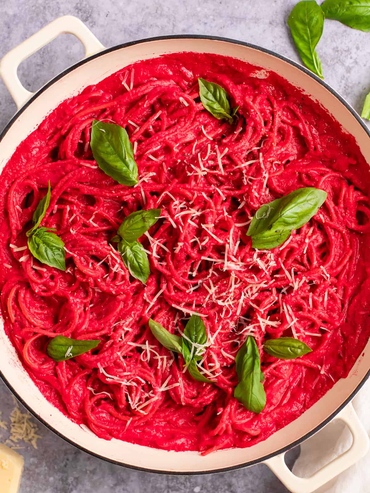 barbie pink beet pasta in a white dutch oven pan with basil and parmesan