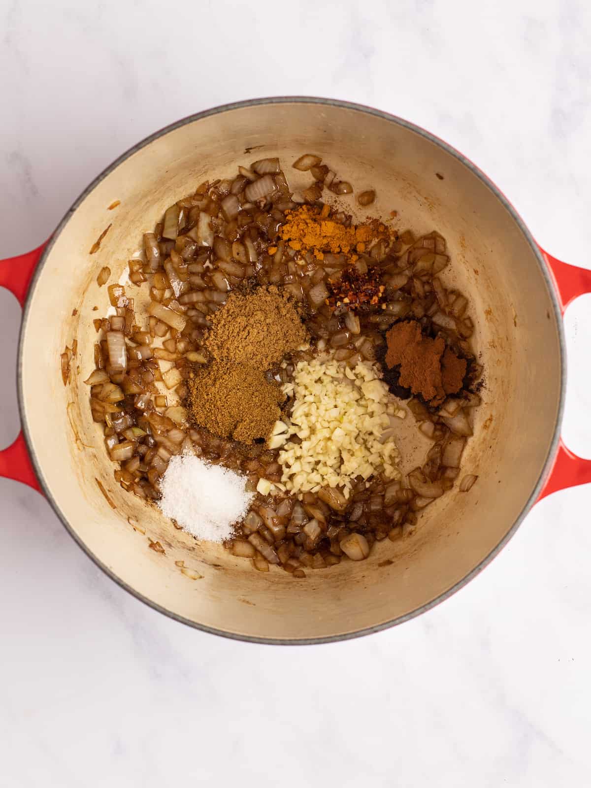 spices and garlic added to dutch oven pan with onions