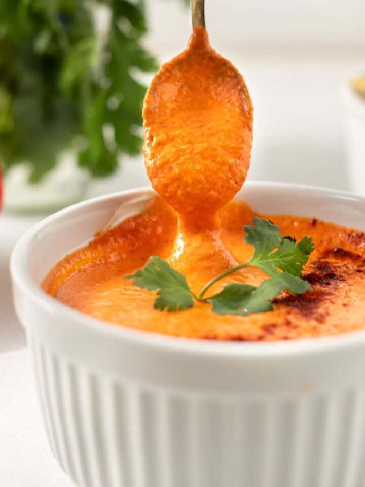 smoky red pepper crema in a white bowl with a spoon