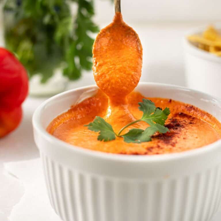 smoky red pepper crema in a white bowl with a spoon