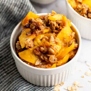 healthy peach crisp in white ramekin