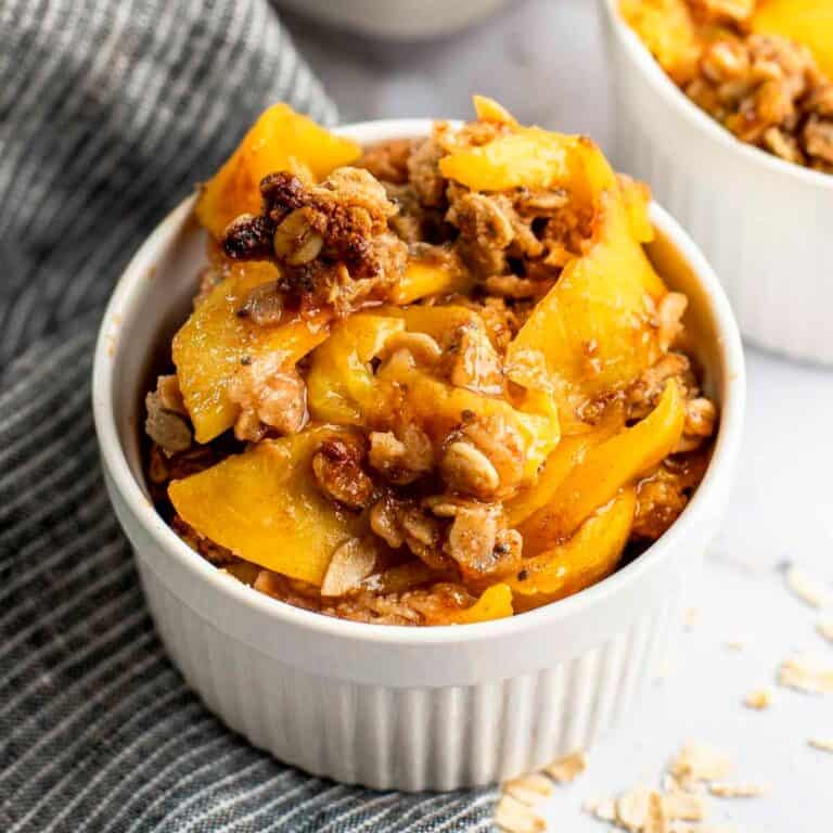 healthy peach crisp in white ramekin
