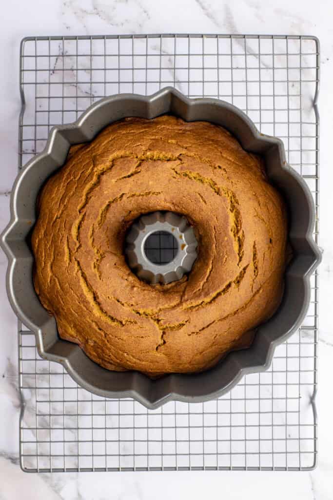 baked gluten free pumpkin cake in a bundt pan on a wire cooling rack