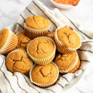pumpkin oat flour muffins in a bowl with a tea towel