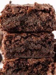 stack of three fudge gluten free brownies on crumbled parchment paper