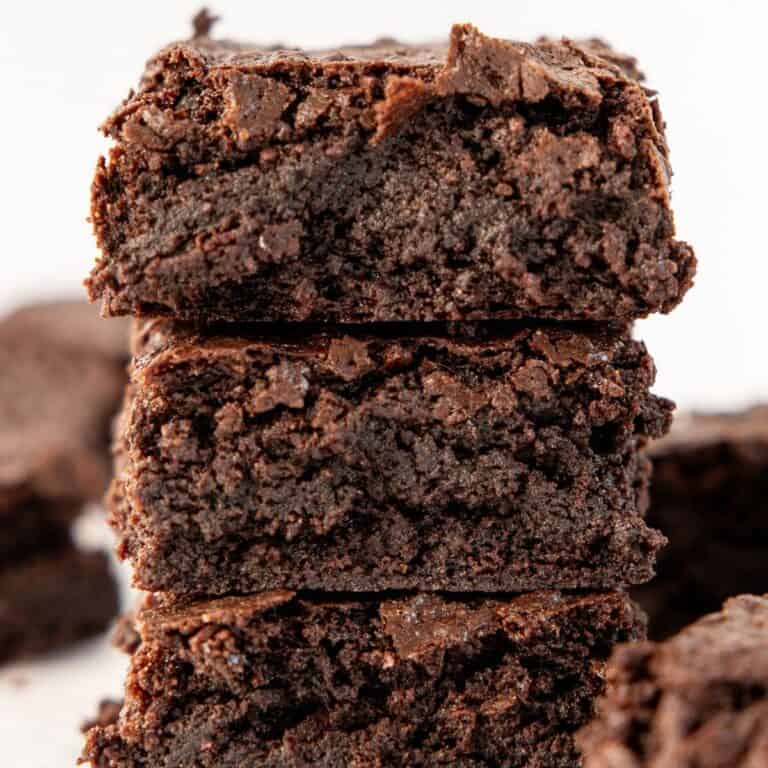 stack of three fudge gluten free brownies on crumbled parchment paper