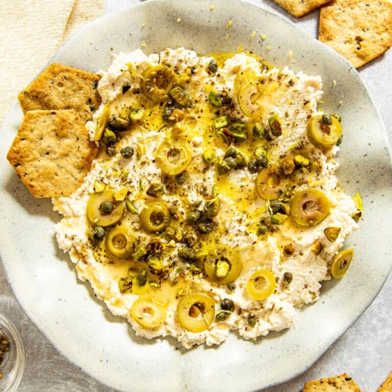 Ricotta Appetizer spread with Olives and Honey on a stoneware plate with crackers