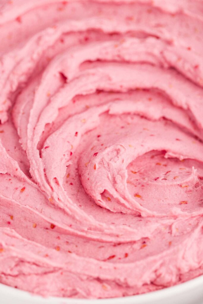 Close-up of smooth, fluffy pink raspberry cheesecake filling swirled in a white bowl