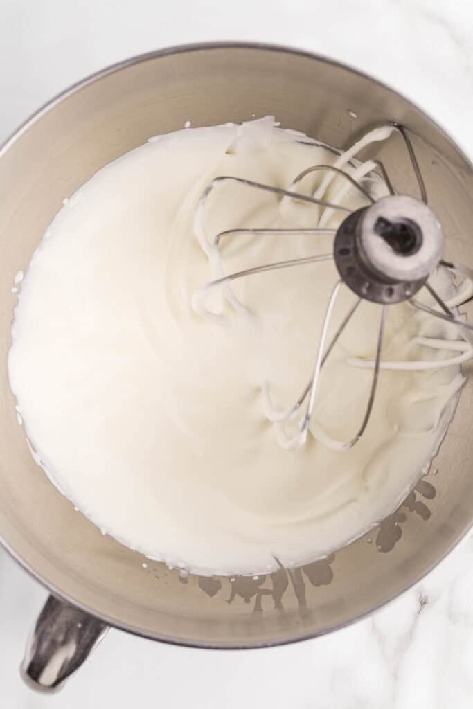 Overhead view of heavy cream whipped to stiff peaks in a stand mixer bowl