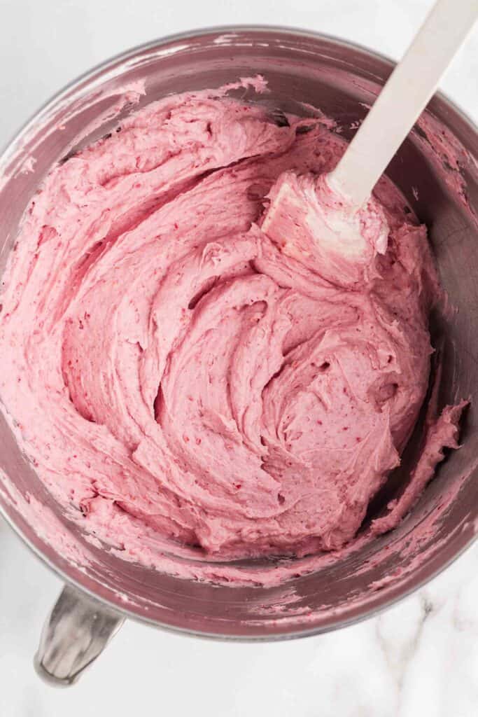 Completed raspberry cheesecake filling in a stand mixer bowl with a pink spatula