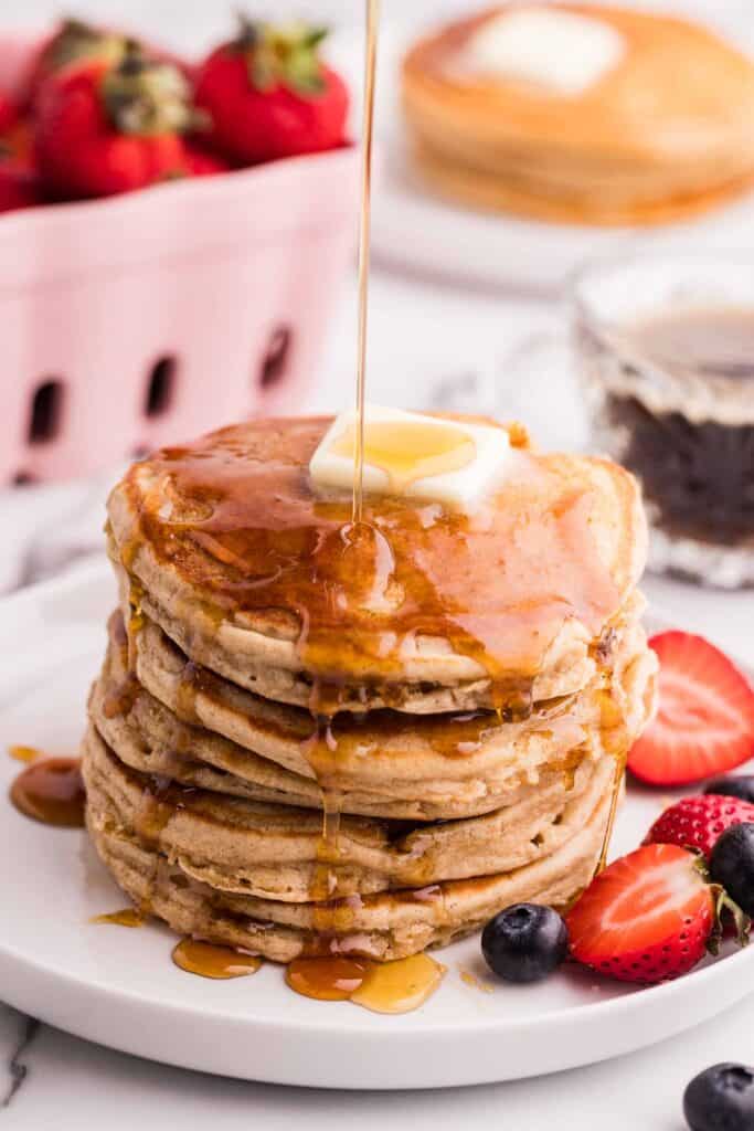 stack of fluffy oat flour pancakes served with maple syrup and fresh berries