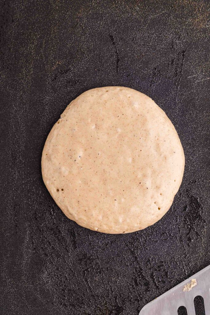 scooping oat flour pancake batter onto a greased griddle