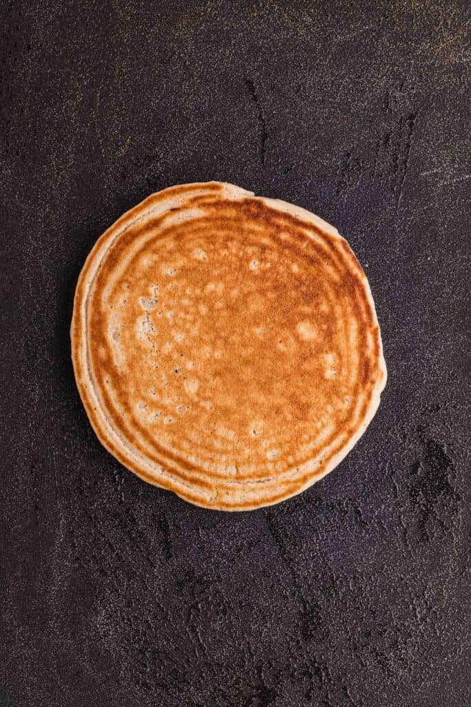 oat flour pancakes cooking on a griddle until golden brown