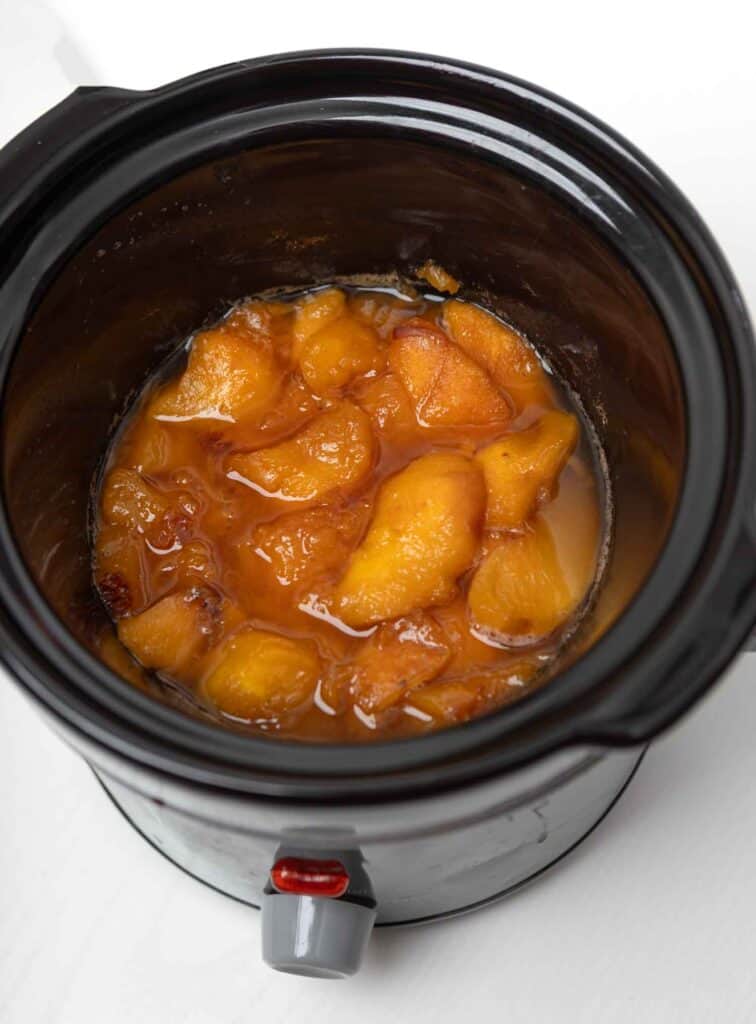 Softened peaches cooking down in the crockpot before blending