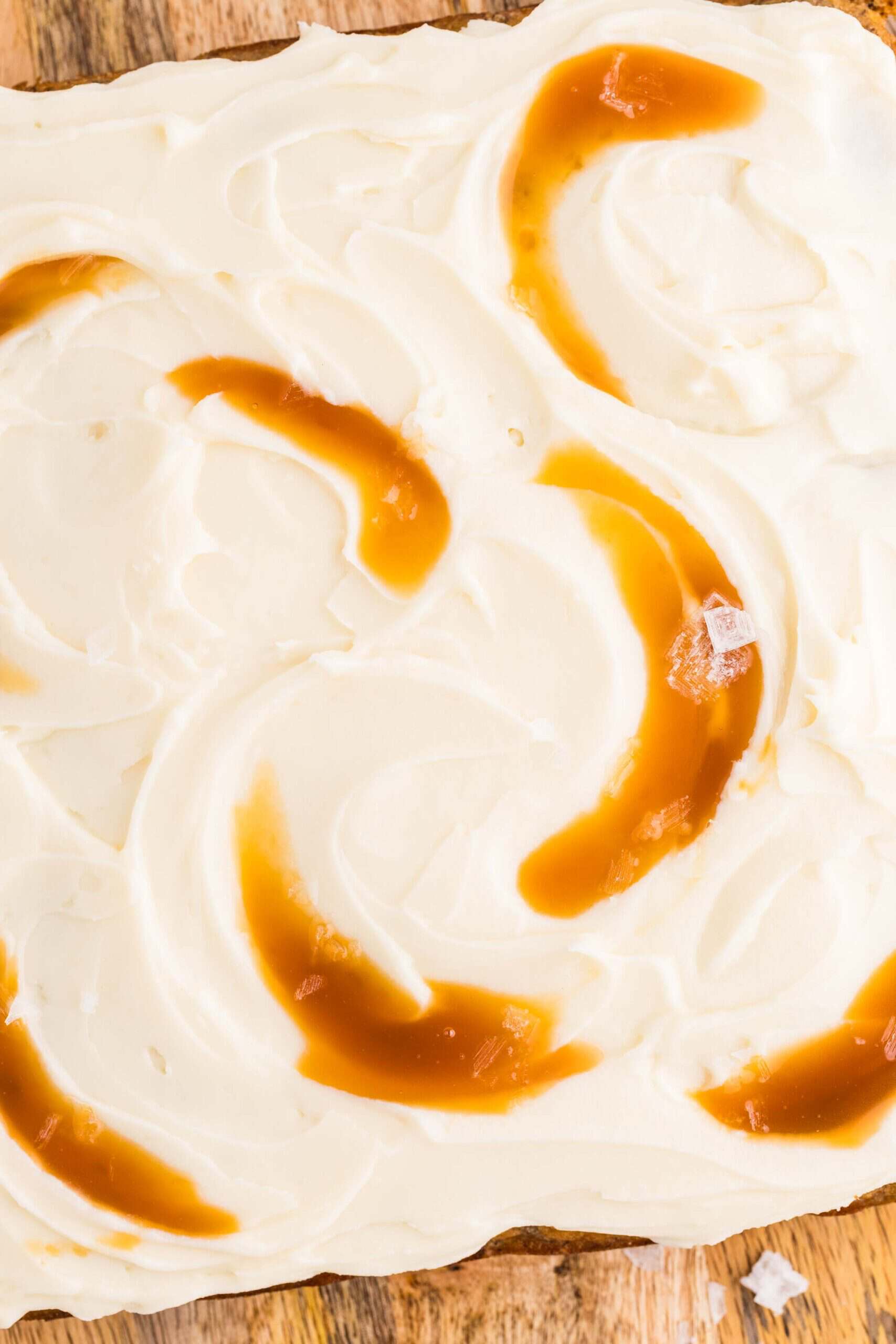 Overhead view of maple cream cheese frosting on a banana cake swirled with caramel
