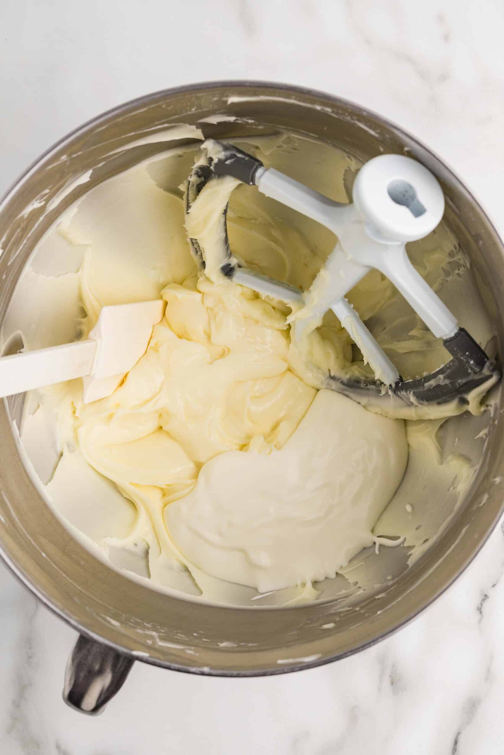 Adding whipped cream to the cream cheese mixture in a stand mixer bowl