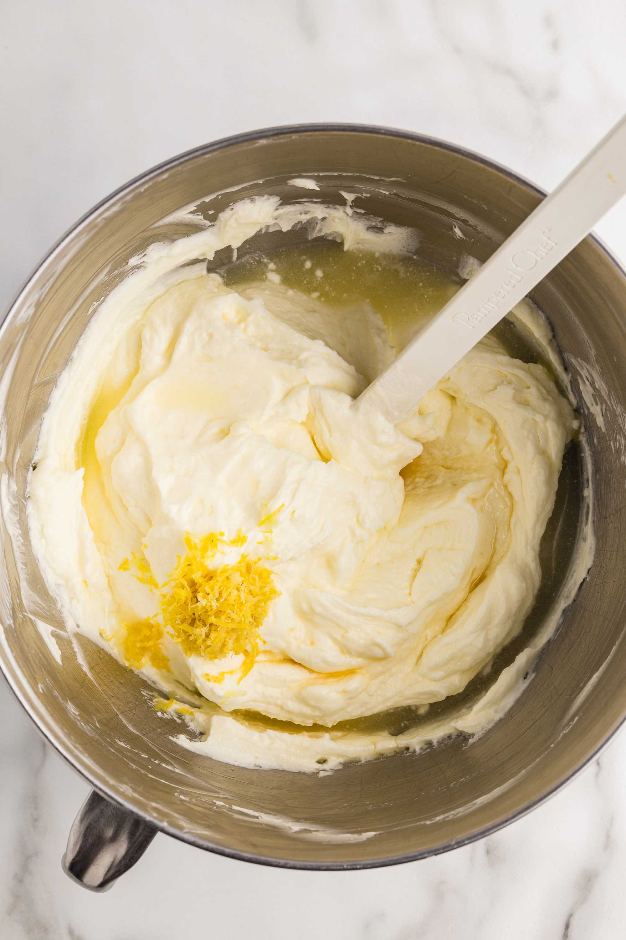 Lemon zest added to the creamy cheesecake filling in a mixer bowl